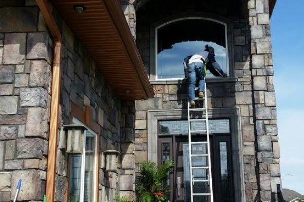 Man on ladder cleaning windows on a home